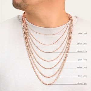 Puede incluir: Primer plano de un hombre que lleva una camiseta blanca con una variedad de cadenas de cuerda de oro rosa de diferentes longitudes y grosores. Las cadenas est&aacute;n etiquetadas con su grosor en mil&iacute;metros y su longitud en pulgadas.  1mm - 18in, 1.5mm - 20in, 1.8mm - 22in, 2mm - 24in, 2.5mm - 26in, 3mm - 28in, 3.5mm - 30in.