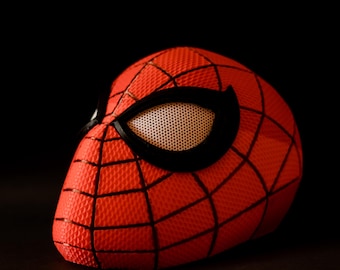 May include: A red and black Spider-Man mask with a detailed web pattern and a black eye mask.