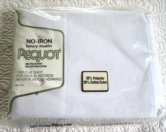 Könnte beinhalten: Ein verpacktes, weißes Twin-Flachbettlaken von Pequot. Die Verpackung enthält ein Etikett mit dem Text "NO-IRON luxury muslin PEQUOT" und Angaben zu den Abmessungen (99x193 cm) und der Materialzusammensetzung (65% Polyester, 35% Baumwolle).