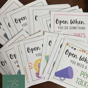 May include: A collection of white rectangular cards with colorful borders and black text. Each card features the phrase Open When followed by specific prompts like you do something that's or you need a pep talk, accompanied by simple illustrations.