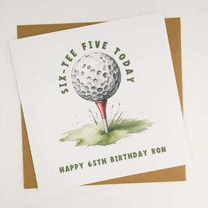 May include: A birthday card with a watercolour illustration of a golf ball on a tee. The card reads "SIX-TEE FIVE TODAY" and "HAPPY 65TH BIRTHDAY RON" in green text. The card is on a brown envelope.