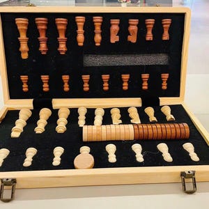 May include: Wooden chess set with a light brown wooden case. The set includes light and dark brown chess pieces, neatly arranged inside a black felt-lined interior. The case is rectangular with a clasp closure.