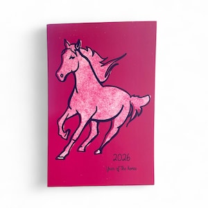 May include: A magenta-colored notebook with a pink horse illustration and the text "2026 Year of the horse." The horse is depicted in a running pose with a textured design and black outlines.