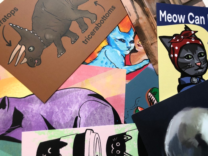 Puede incluir: Una colecci&oacute;n de tarjetas coloridas con varias ilustraciones. Una tarjeta presenta un triceratops de dibujos animados con el texto "triceratops" y flechas que apuntan a su cabeza y cola. Otra tarjeta presenta un gato de dibujos animados con un pa&ntilde;uelo rojo con lunares blancos y el texto "Meow Can Do".
