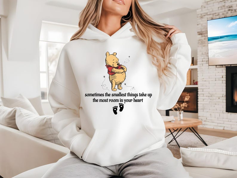 May include: White hoodie with a Winnie the Pooh illustration and the text "sometimes the smallest things take up the most room in your heart".