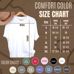 May include: A white t-shirt hanging on a wooden hanger, with a size chart and color options displayed. The size chart shows measurements in inches for width and length, ranging from size small to 3XL. Color choices include light green, red, and black.