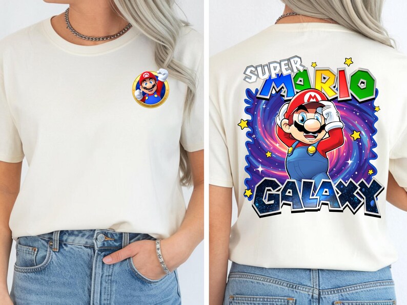 May include: Off-white t-shirt featuring a colorful graphic of Mario from Super Mario Galaxy. The front has a small Mario graphic, while the back displays a larger design with the text "SUPER MARIO GALAXY" and star accents. The shirt is paired with blue jeans.