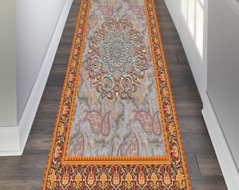May include: A decorative rug featuring a large, intricate, light blue and brown mandala design in the centre. The rug has a red, orange, and yellow border with a floral pattern.