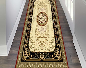 May include: A long runner rug with an intricate floral pattern in red, black and gold. The rug has a cream background and a red border.
