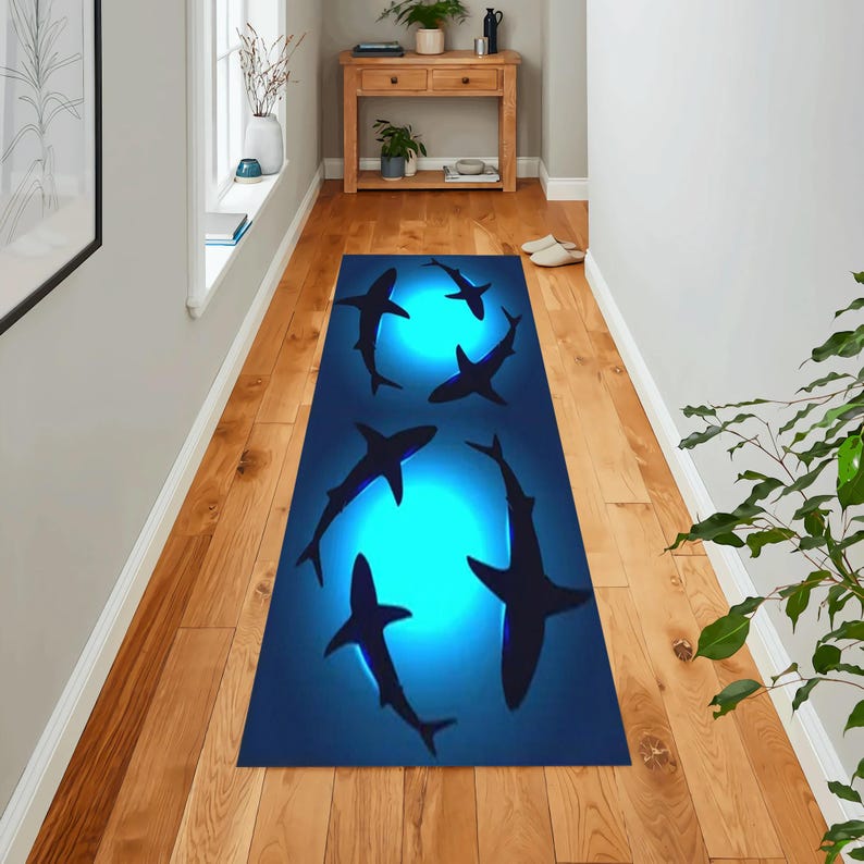 May include: A blue and black runner rug with a design of sharks swimming in a circle around a glowing moon. The rug is perfect for a hallway or entryway.