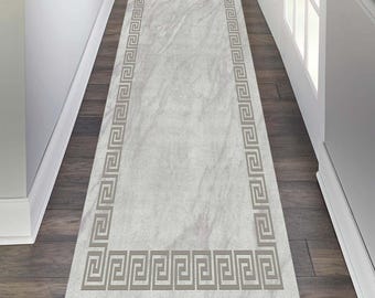 May include: A white runner rug with a grey Greek key border. The rug is on a hardwood floor.