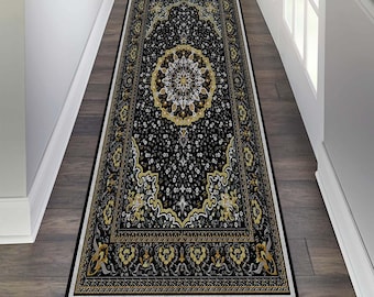 May include: A black runner rug with a detailed floral pattern in gold, cream, and white. The rug has a central medallion design and ornate borders. It is placed on a wooden floor, adding a decorative element to a hallway or corridor.