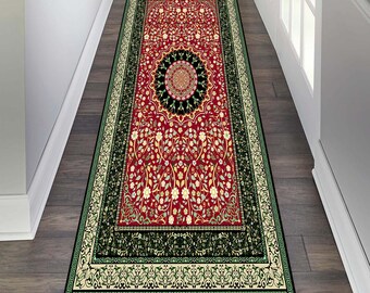 May include: A red, green and cream patterned runner rug with a floral design. The rug has a black border with intricate details.