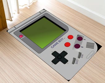 May include: A gray and black Game Boy rug with a green screen, red and purple buttons, and the text "GAME BOY TM".