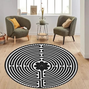 May include: Black and white circular rug with a labyrinth design. The center of the rug features a stylized flower with a circle in the middle.