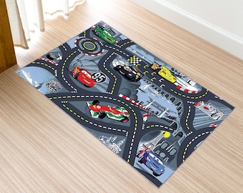 May include: A gray and blue rug with a race track design featuring various cartoon cars. The cars are red, yellow, green, and blue. The rug has a white border and the words "Go Fast" are printed on the rug.