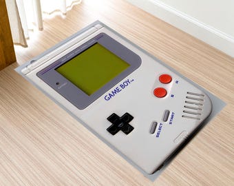 May include: A white Game Boy handheld video game console with a gray screen and red buttons. The console has the text "GAME BOY" printed on it.
