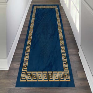 Puede incluir: Una alfombra de pasillo azul con un borde dorado de clave griega. La alfombra está hecha de un material suave y duradero y es perfecta para agregar un toque de elegancia a cualquier hogar.