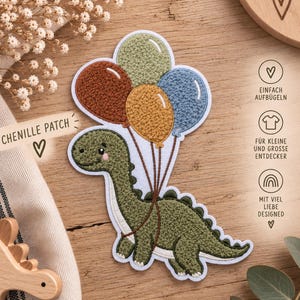 Könnte beinhalten: Ein Chenille-Aufnäher mit einem grünen Dinosaurier, der ein Bündel aus vier Luftballons in Salbeigrün, Rostbraun, Senfgelb und Staubblau hält. Der Dinosaurier hat einen weißen Bauch und ein lächelndes Gesicht, verbunden mit dünnen braunen Schnüren.