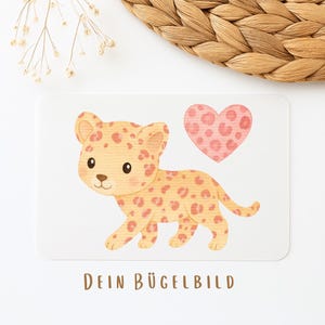Könnte beinhalten: Rechteckige Karte mit einem Cartoon-Leoparden und einem rosa Herz. Der Leopard hat orangefarbene Flecken auf einem hellbraunen Körper. Das Herz ist rosa mit orangefarbenen Flecken. Der Text "DEIN BÜGELBILD" steht unten.