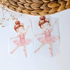 Könnte beinhalten: Zwei Aquarellillustrationen einer Ballerina in einem rosa Tutu und Ballettschuhen. Die Ballerina hat braunes Haar, das zu einem Dutt mit einem Blumenkranz gestylt ist. Die Illustrationen befinden sich auf weißem Hintergrund.