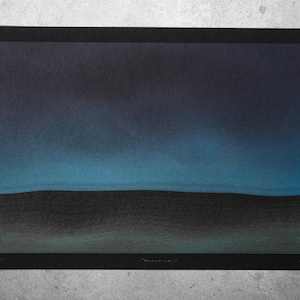May include: A framed art print depicting a dark landscape. The artwork uses a gradient of blues and blacks, evoking a night sky above a dark, textured terrain. The print is set within a black frame.