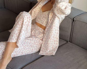 Puede incluir: Un conjunto de pijama de leopardo blanco y rosa con camisa de manga larga y pantalón.