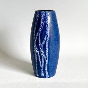 Può includere: Un vaso in ceramica blu con un design astratto bianco. Il vaso è alto e sottile con un fondo arrotondato.