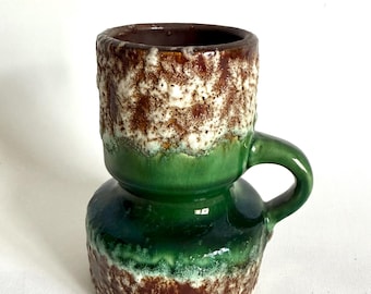 May include: A ceramic mug with a unique design. The mug features a textured brown and white top, a vibrant green middle section, and a dark brown base. It has a small handle and a dark brown interior.
