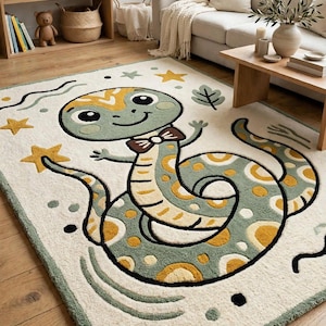 May include: A rectangular area rug featuring a central cartoon snake with a light green body, yellow spots, and a brown bow tie. The cream-colored background is decorated with yellow and green stars, wavy lines, and leaf motifs, all outlined in black.