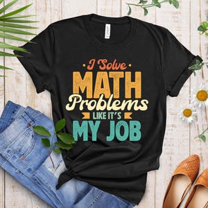 Può includere: Maglietta nera con una grafica in stile vintage che dice "I Solve Math Problems Like It's My Job".