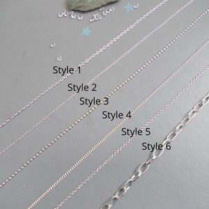 May include: Six silver-toned metal chains arranged diagonally, labelled Style 1 through Style 6. The chains vary in link design, ranging from fine cable and ball chains to a larger oval link chain, all displayed against a plain grey background.