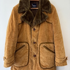 May include: A vintage corduroy coat in a warm tan color, featuring a dark green faux fur collar and trim. The coat has large front pockets, button closures, and a label that reads "Showhouse".