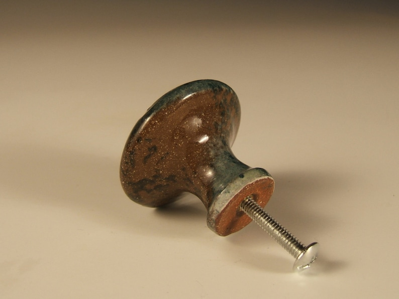 May include: A brown and green ceramic cabinet knob with a silver screw.