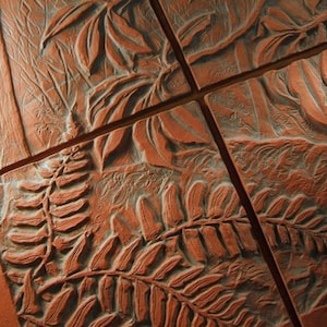May include: Terracotta tiles with a relief design of a forest scene. The design includes ferns, leaves, and tree trunks. The tiles are arranged in a grid pattern, with visible lines separating each tile.
