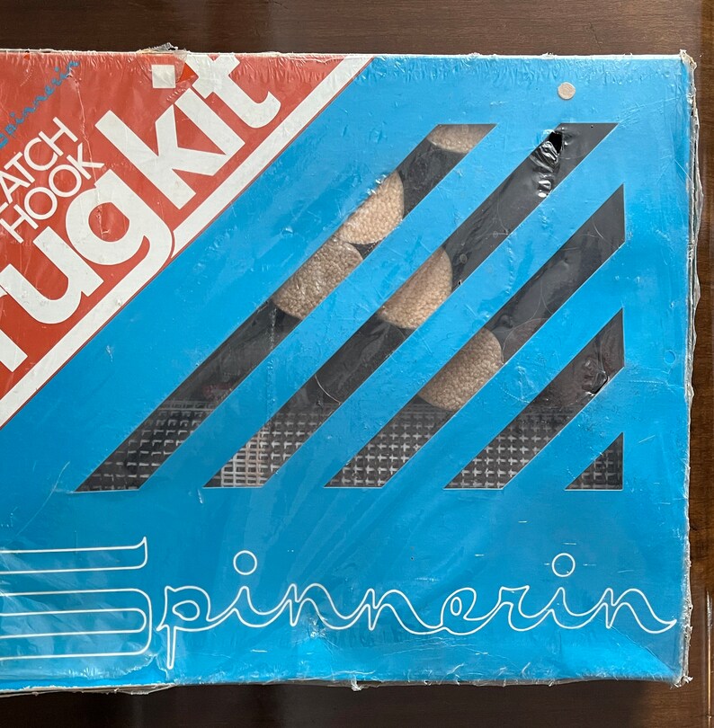 May include: A blue and white rug kit with the text "Rug Kit" and "Latch Hook" on the front. The kit includes yarn, a canvas, and a latch hook tool.