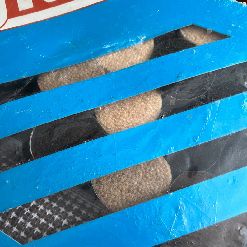 May include: Close-up of a blue and black package with five beige round objects inside. The objects are visible through a clear plastic window.