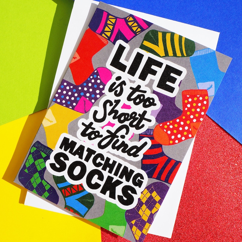 May include: A gray card with a colorful sock pattern and the text "Life is too short to find matching socks".