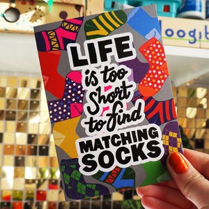May include: A gray card with a colorful sock pattern and the text "LIFE is too short to find MATCHING SOCKS".