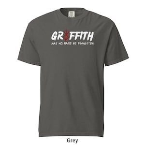 May include: A grey t-shirt with a white graphic print that says "Griffith" with a red and black symbol above the text. The text below the symbol says "May his name be forgotten".
