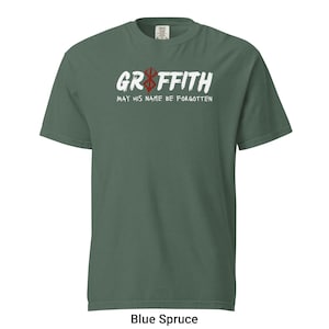 May include: A green t-shirt with a white graphic that says "Griffith" with a red and white symbol above the text. The text below the graphic says "May his name be forgotten".