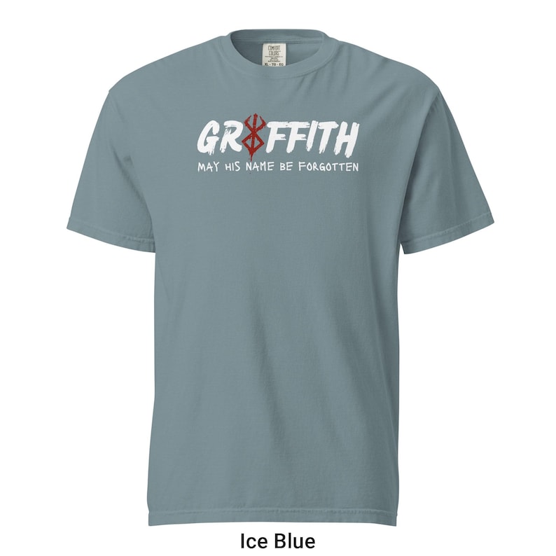 May include: A light blue t-shirt featuring a white graphic that reads "Griffith" with a red symbol above the word. The text below the graphic says "May his name be forgotten".
