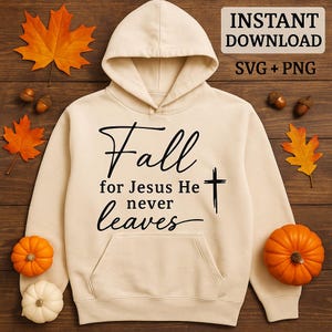May include: A cream-colored hoodie with the words "Fall for Jesus He never leaves" in black script and a cross graphic. The hoodie has a hood and a front pocket. The image includes pumpkins, leaves, and acorns.
