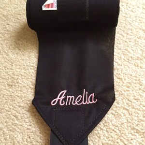 Puede incluir: Vendas negras para las piernas de caballo con cierre de velcro y el nombre Amelia bordado en rosa.