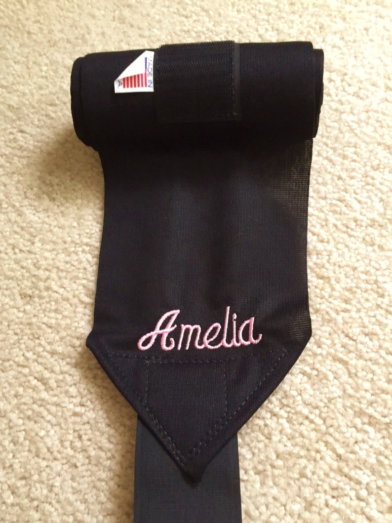 Puede incluir: Vendas negras para las piernas de caballo con cierre de velcro y el nombre Amelia bordado en rosa.