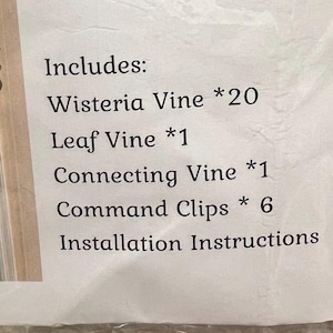 Peut inclure: Une liste imprim&eacute;e des &eacute;l&eacute;ments inclus dans un kit de d&eacute;coration de porte de glycine. La liste comprend 20 vignes de glycine, 1 vigne de feuilles, 1 vigne de connexion, 6 clips de commande et des instructions d'installation.