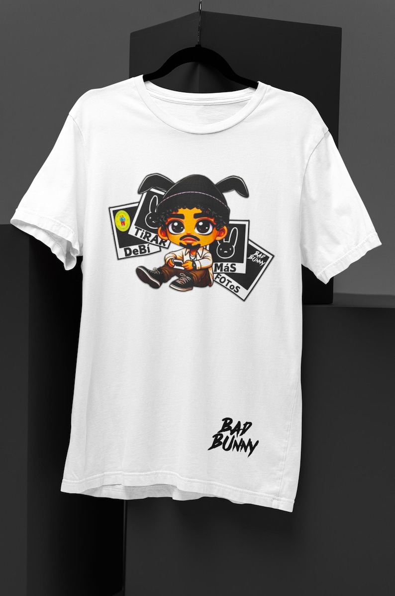 May include: White t-shirt featuring a cartoon illustration of a person with a black hat and mustache. The shirt has the text "BAD BUNNY" in black script and several graphic elements with text in Spanish.