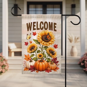 May include: A rectangular garden flag featuring a beige and white buffalo check background with the word WELCOME in brown text. The design includes yellow sunflowers, orange and white pumpkins, red maple leaves, and two butterflies.