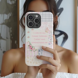 May include: A white phone case with a patchwork design featuring pink, green, and blue colors. The case has a quote that reads "I can do all things through Christ who strengthens me."  Philippians 4:13.