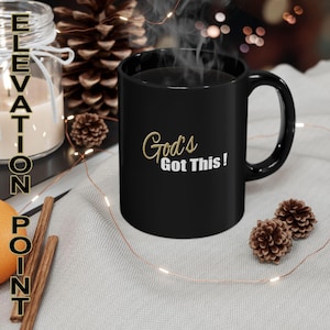 May include: Black coffee mug with a white inscription that reads "God's Got This!" in gold lettering.